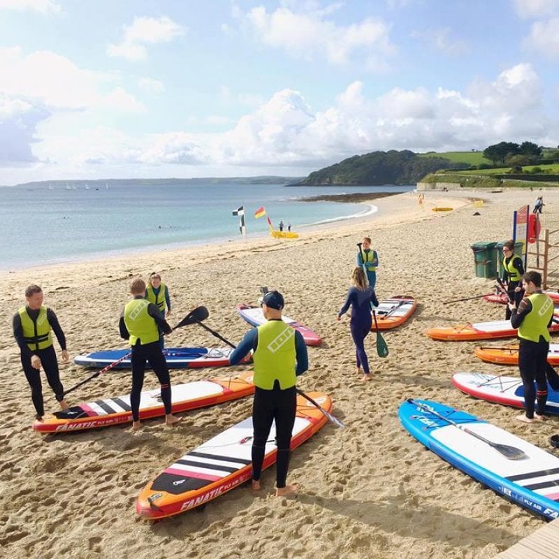 A group of Falmouth University students with paddle boards on Gylly Beach